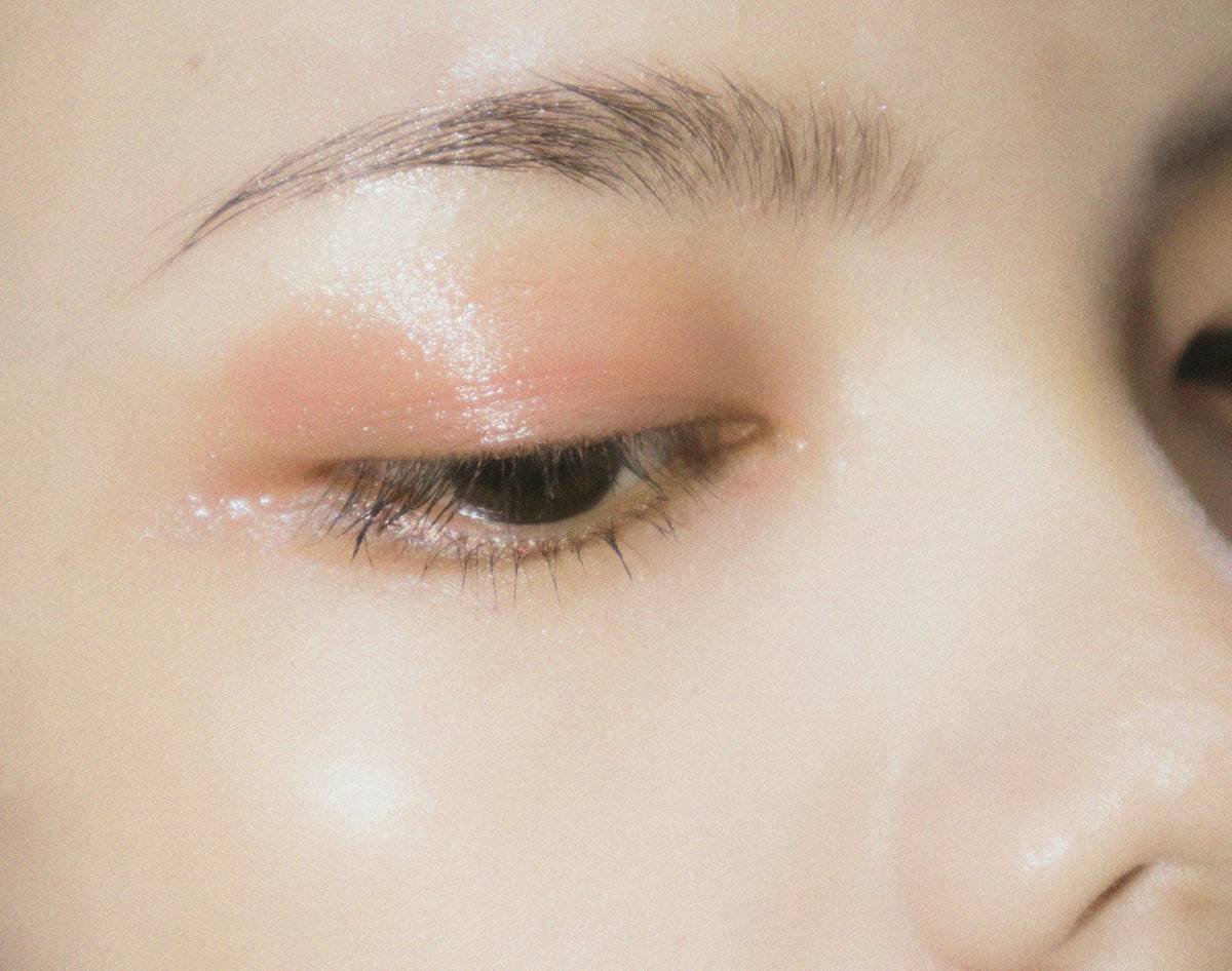Close-up of sponge makeup blending technique showing tapered tip reaching under eyes